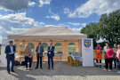 Die Festredner, drei Männer und eine Frau, stehen vor einem Pavillon. Rechts steht ein Rollup mit dem Wappen von Dasing.