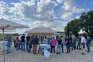 Zahlreiche Zuhörer verfolgen die Ausführungen der Redner. Diese stehen vor einem Pavillon. 